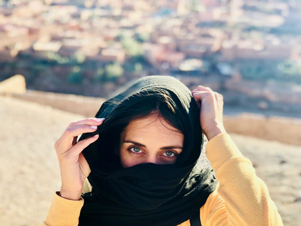 Woman wearing a traditional Moroccan scarf walking in Marrakech market, Morocco